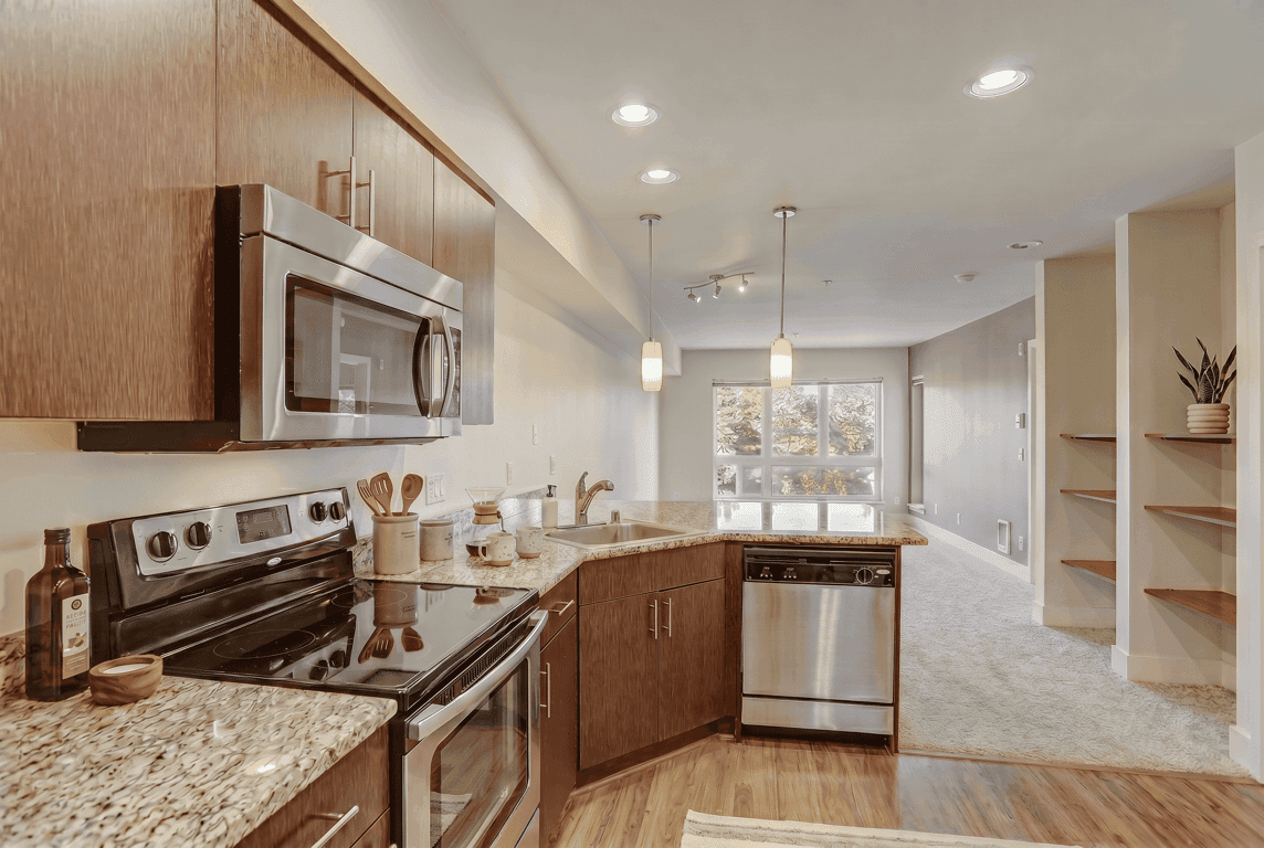 Modern kitchen with granite counters, wood cabinets, stainless steel appliances, and open concept...